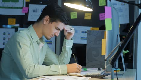 overworked businessman working late at night in the office, his desk is covered with paperwork, work overtime and deadlines concept