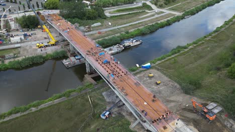 Aerial-panning-view-to-the-right-overlooking-construction-site-of-bridge-for-pedestrian-and-bicycles-over-Warta-river-in-Poznan-Poland-during-summer-sunny-day