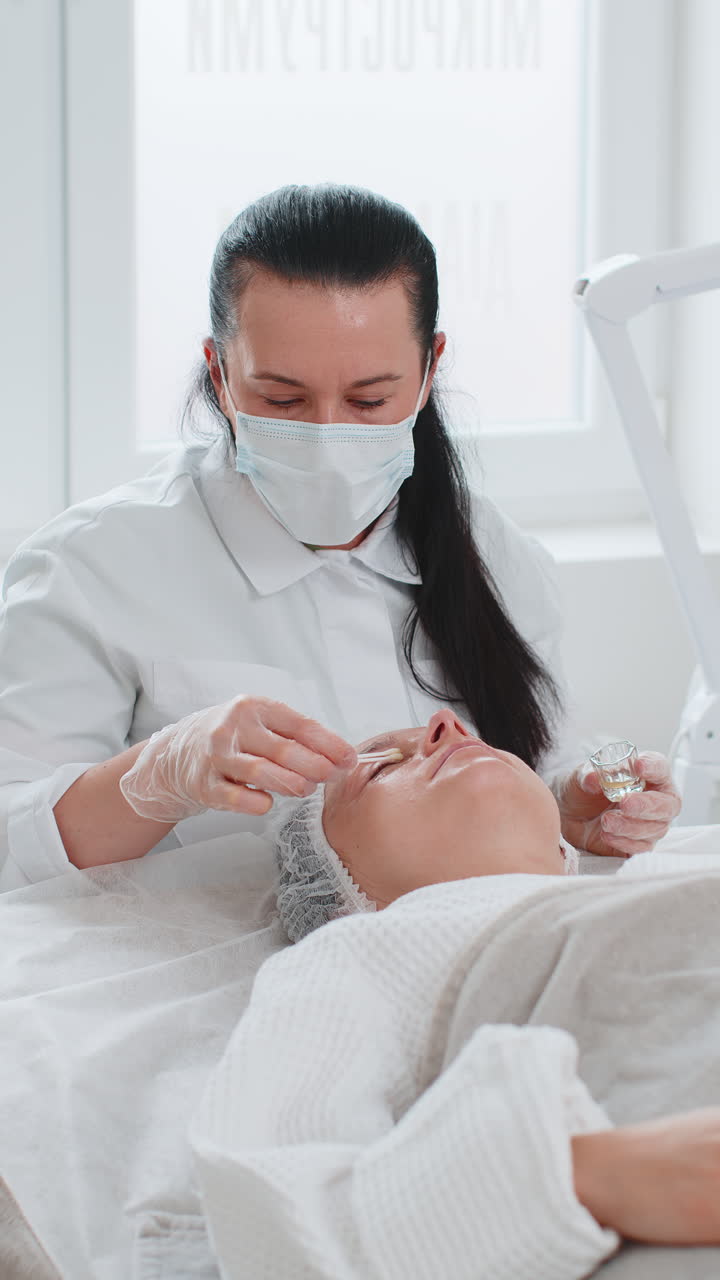 esteticista aplicando hidratante química médica peeling máscara de ácido en la cara y los ojos de una mujer joven
