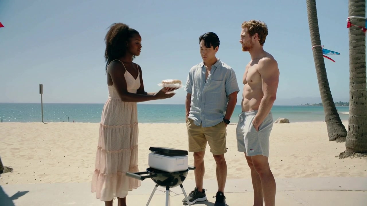 Unpacking cooler woman in flowy dress placing buns on grill beach walkway, offering food to men