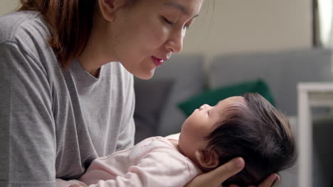 mother and baby girl making eye contact and having a tender moment at home, as the mother soothes her baby to sleep with love and care, displaying nurturing affection