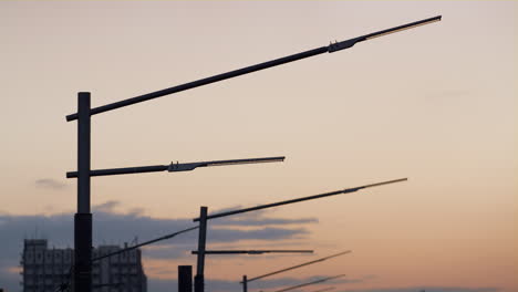 Closeup-powerful-street-lamps-silhouettes-drone-shot.-Dark-lamppost-metal-poles.