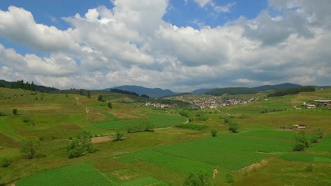 Grünes-Ackerland-In-Der-Nähe-Eines-Kleinen-Dorfes