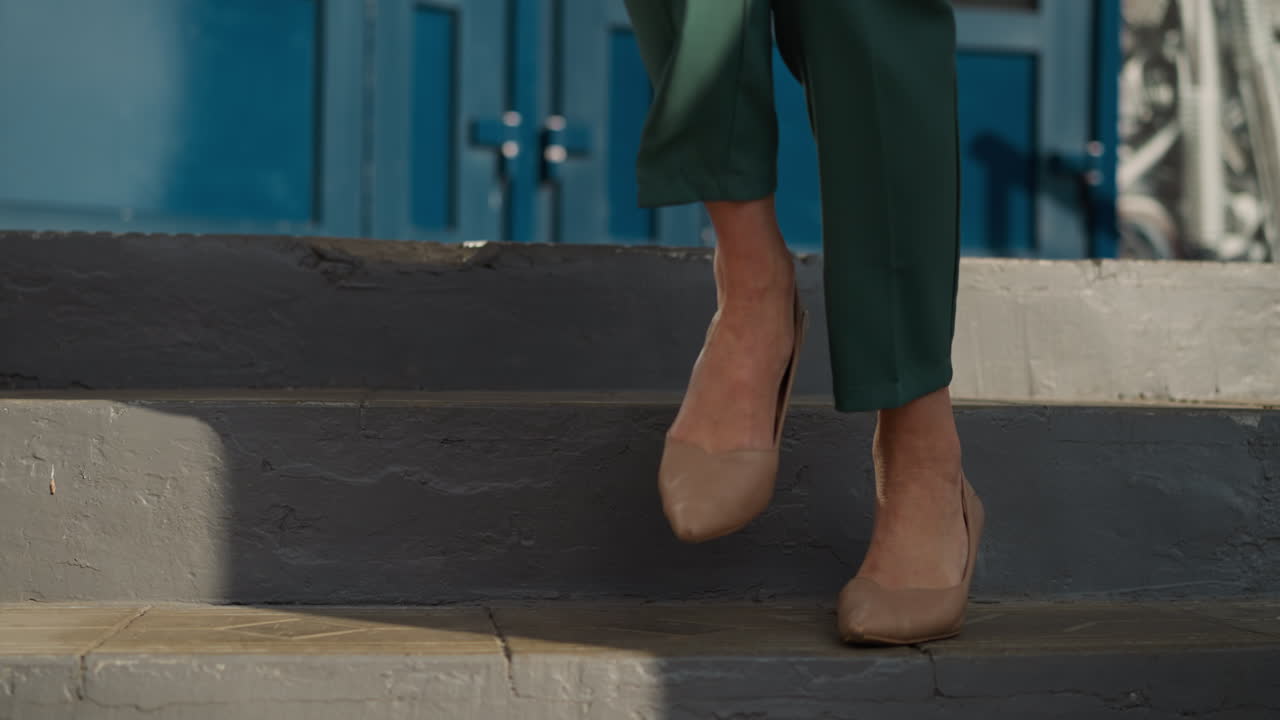 las piernas femeninas en zapatos de tacón alto beige bajan las escaleras.