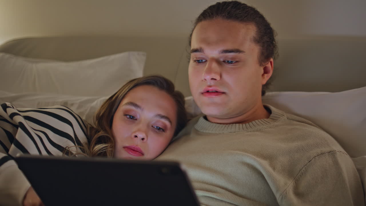 Family watching social media on tablet lying cozy bed closeup. Romantic spouses