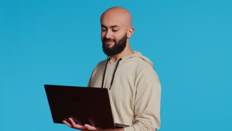 Young-adult-waving-at-videocall-connection-on-laptop