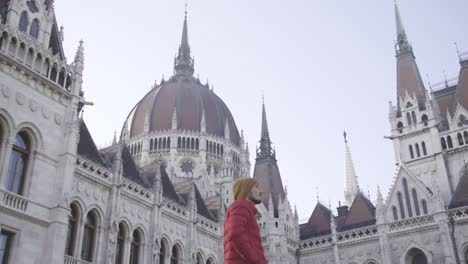 Man-looking-around-Parliament-building,-Budapest-Europe,-low-angle