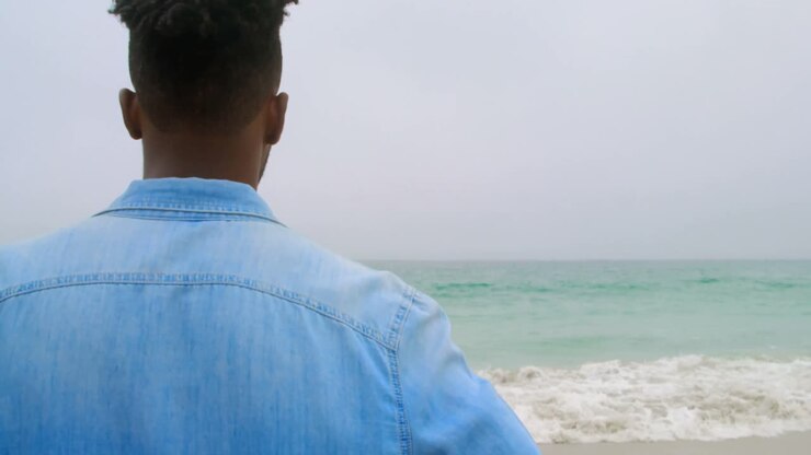 Vista posteriore di uomo afroamericano in piedi sulla spiaggia 4k
