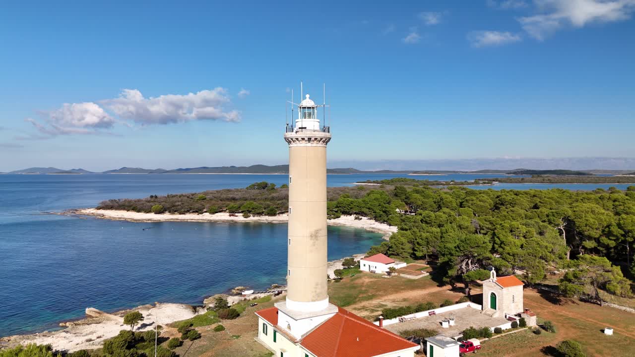 Rotating drone aerial around lighthouse tower of the Veli Rat on Dugi Otok, Croatia.Coastline with turquoise Adriatic Sea, and bright sunny weather in Zadar county