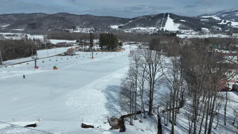 Schnelle-Kamerafahrt,-Die-Den-Berg-Hinunterfliegt-Und-Dem-Sessellift-Der-Seilbahn-Folgt,-Skifahrer-Fahren-Die-Pisten-Darunter-Hinunter