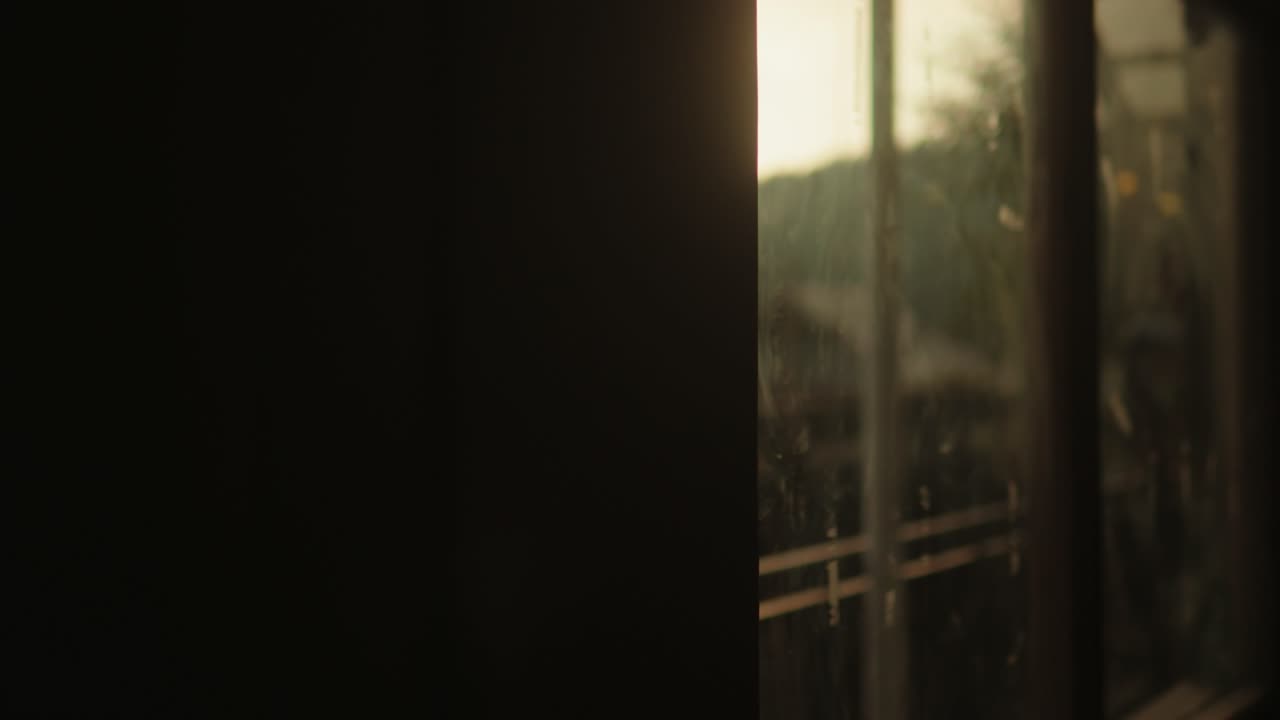 Sunset glow through a window, with a glimpse of tracks and poles, evoking travel nostalgia
