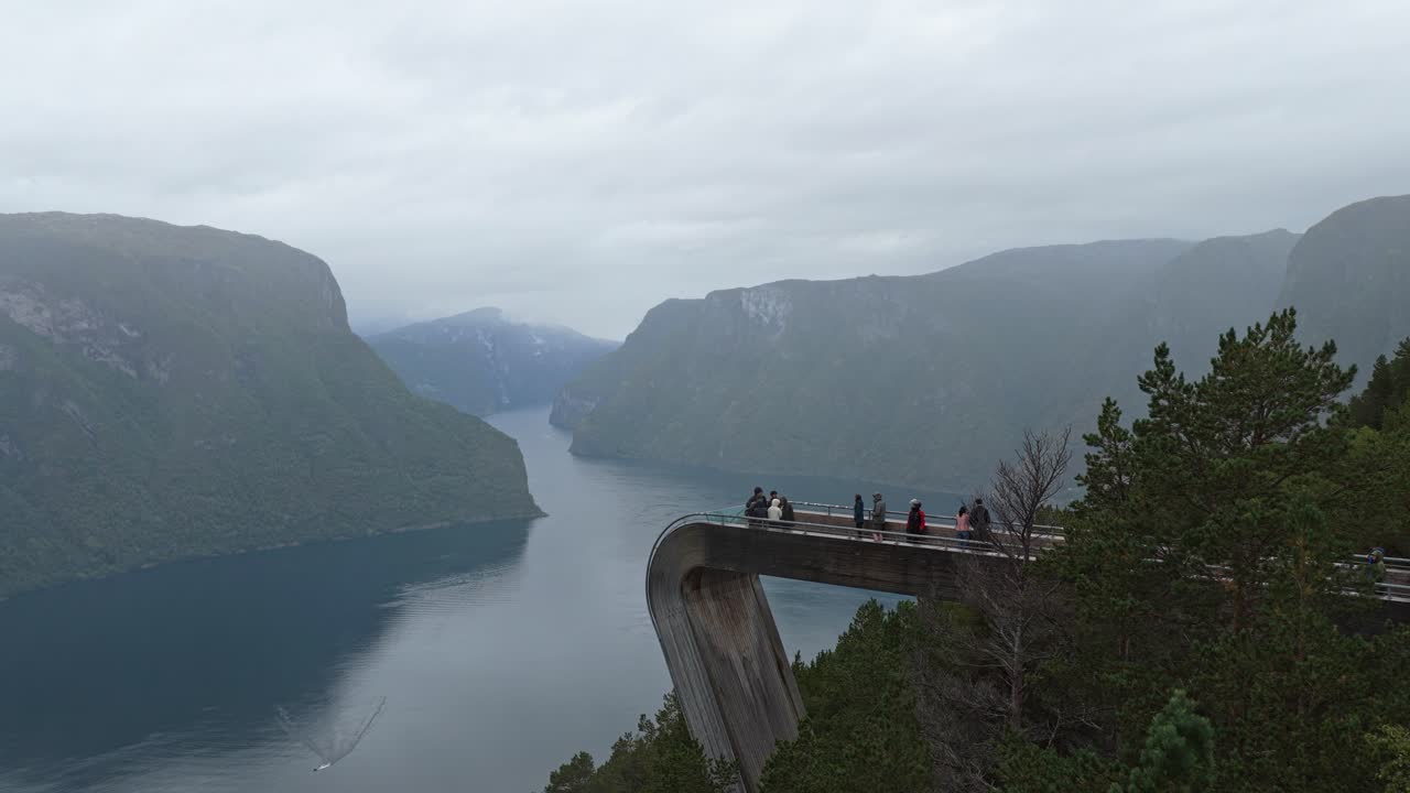 Stegastein view platform perched over fjord landscape with tourists, seen from drone, Norway