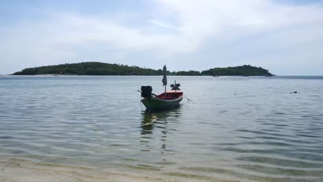 Long-tail-boat-floating-in-shallow,-calm-sea-off-Samui-Island,-Thailand