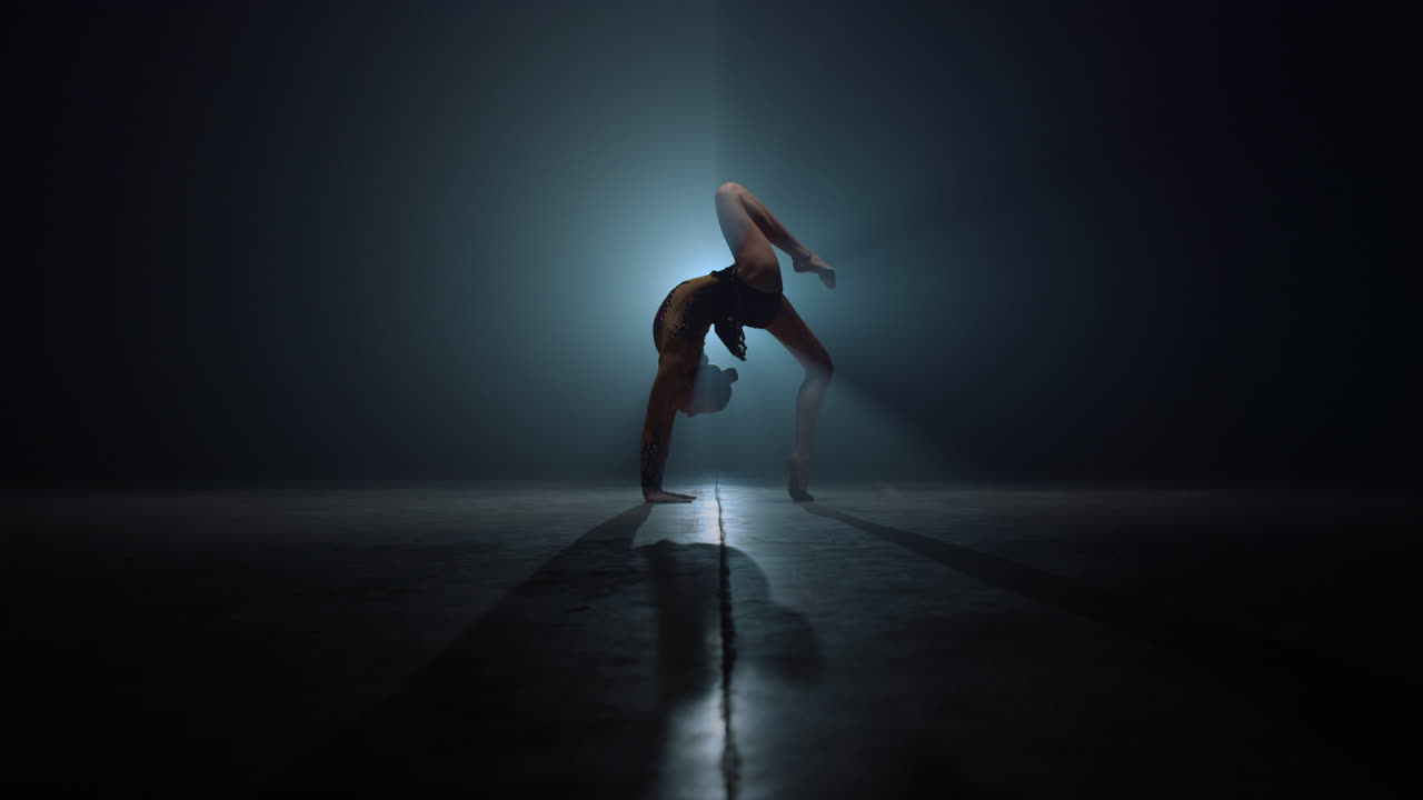 Flexible gymnast doing backbend exercises. Beautiful woman stretching indoors.