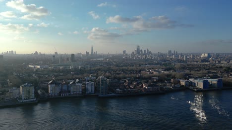 Vista-De-ángulo-Alto-Del-Río-Támesis-Sobre-La-Granja-De-Surrey-Docks,-El-Horizonte-De-Londres-En-La-Distancia