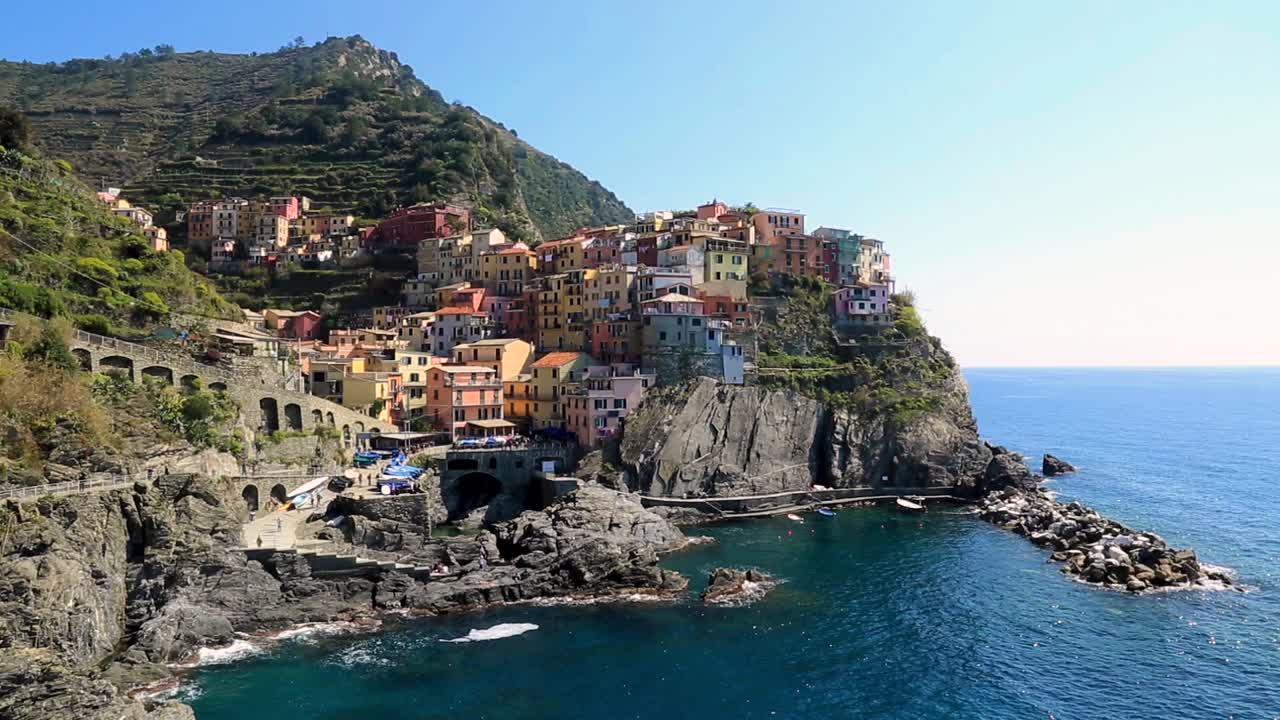 vista statica sulla costa di manarola, porto e baia con case colorate e acqua turchese in una soleggiata giornata estiva a vernazza, cinque terre, liguria italia
