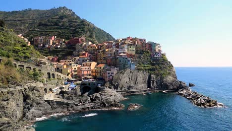 static view overlooking manarola coastline, harbor and bay with colorful houses and turquoise water on a sunny summer day in vernazza, cinque terre, liguria italy