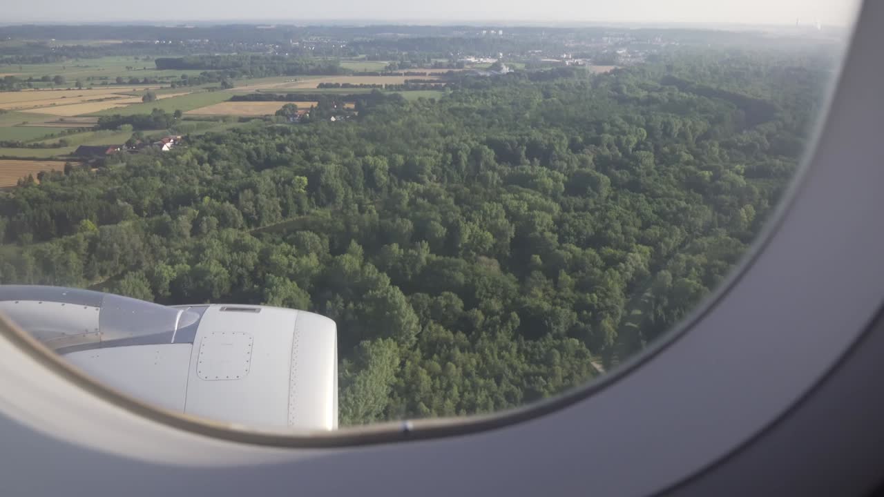 поля, деревья, река и европейские поселения, видные через окно самолета.