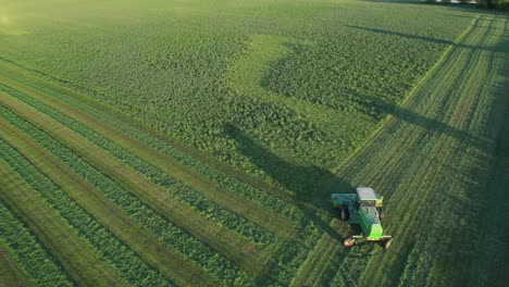 In-Door-County,-WI,-a-farmer-on-a-John-Deere-tractor,-cuts-his-alfalfa-field-in-late-August-10