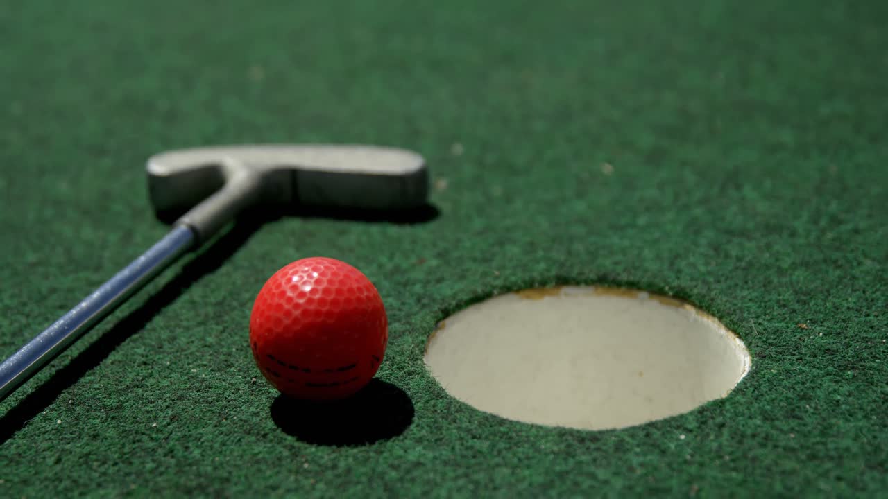 putter de golf y pelota de golf en un césped artificial 4k