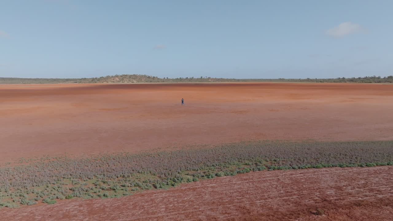 A Solitary Figure Walking Across a Vast Red Landscape