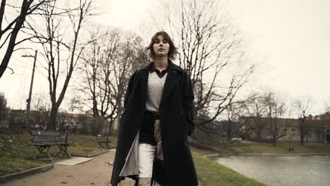 Mujer-Joven-Con-Un-Abrigo-Negro-Caminando-En-Un-Parque-En-Otoño-Por-La-Tarde-2