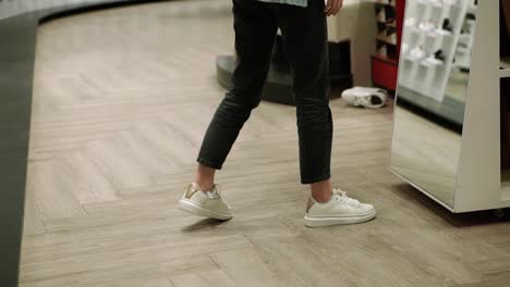 woman fits new white sneakers in shoe store, trying best size