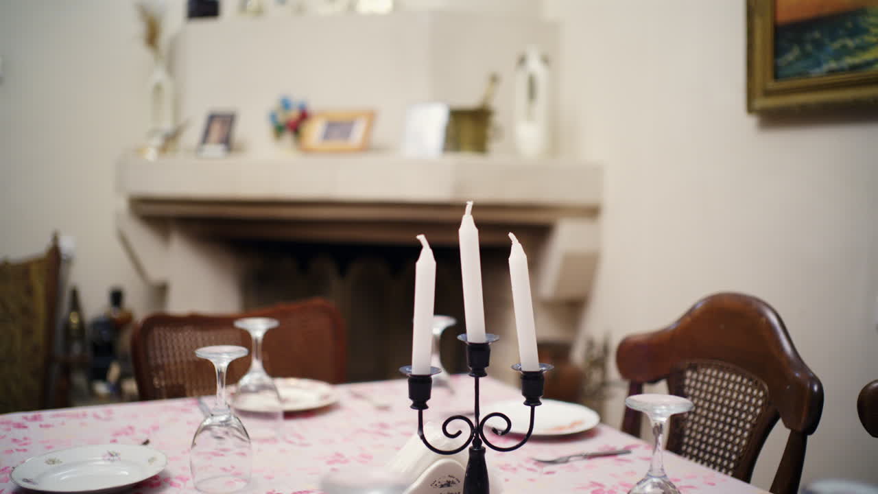 Dining table set with plates, glasses, and white candles in a cozy home interior