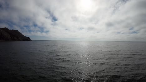 Drone-Vuela-Sobre-El-Mar-En-Un-Ambiente-Oscuro-Con-El-Cielo-Muy-Iluminado-En-Vuelo-Muy-Cerca-Del-Mar