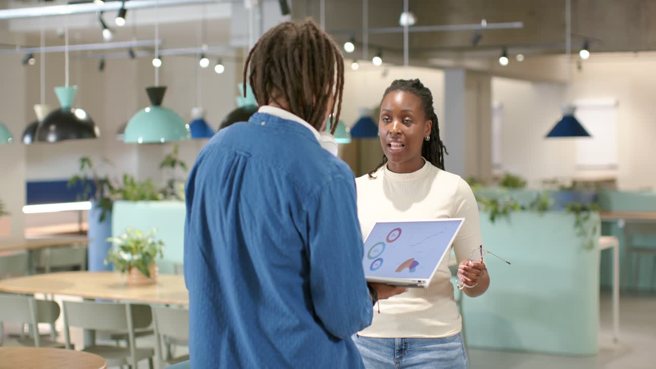 African American team examining laptop, man offering screen, woman holding glasses reviewing plan