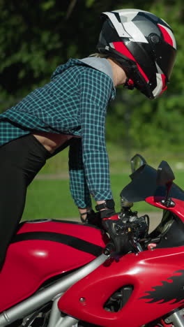 a side view of a lady riding a red power bike, wearing a helmet, as she stands up and then sits back on the bike, her shirt flutters in the wind, revealing part of her back on a bright sunny day