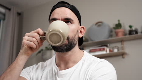 hombre bebiendo café mientras escribe un diario en casa - de cerca