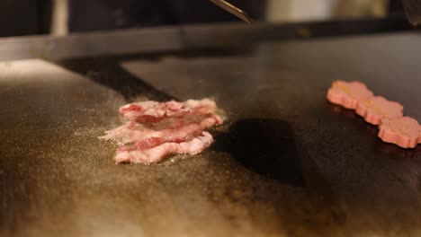 sizzling bacon strips being flipped on a griddle