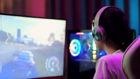 primer plano de una adolescente asiática que usa auriculares y juega videojuegos en la computadora, juega un videojuego de carreras