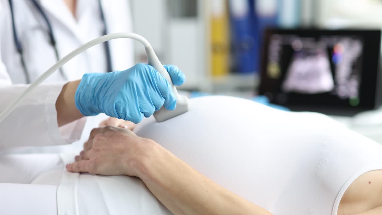 Un medico esegue un'ecografia prenatale esaminando l'immagine del feto.