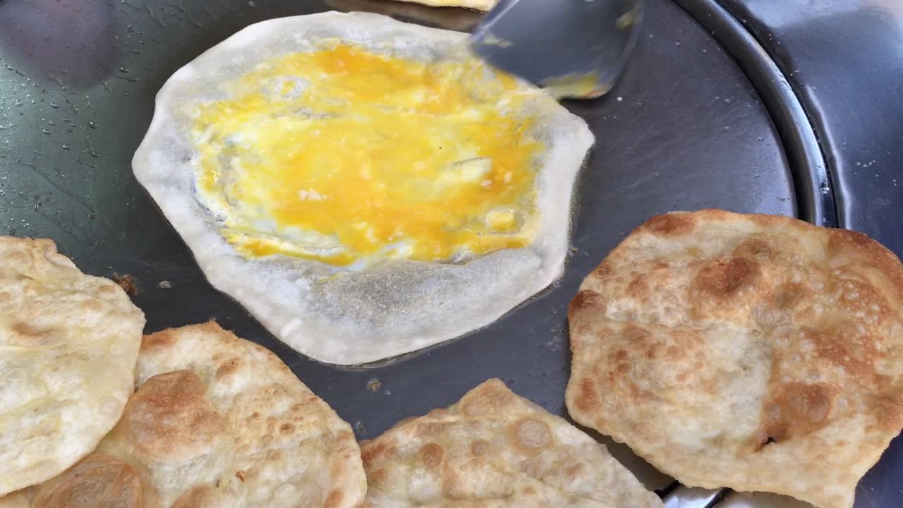 cocinar panqueques tailandeses exóticos, roti malaysian con diferentes rellenos en un mercado de tailandia. hacer rollo de roti de huevos en sartenes de metal calientes con aceite hervido. comida callejera de tailàndia. postre tailandés.