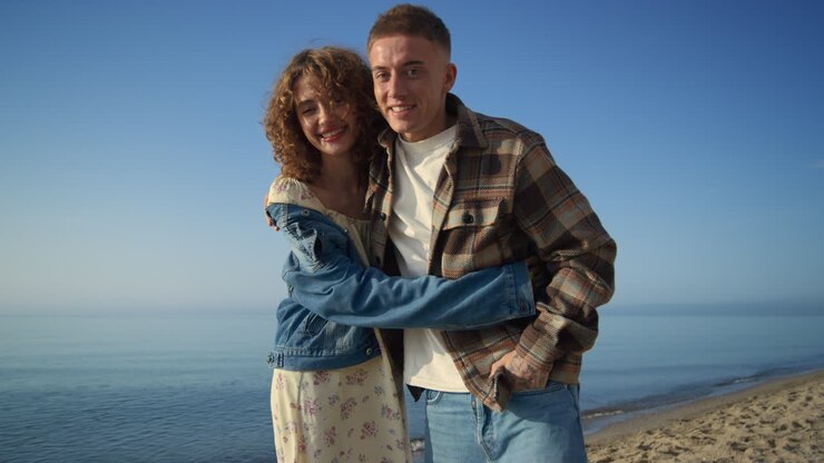 Couple joyeux en rendez-vous sur une magnifique côte maritime. Un bel homme embrasse une fille enjouée.