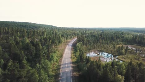 Forward-drone-shot-over-forests-in-northern-Finland-following-a-motorcyclist