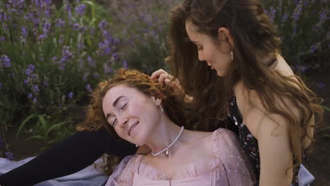 Curly-women-among-a-lavender-field,-embracing,-enjoying-each-other