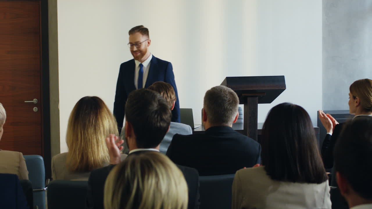 Caucasian male business speaker finishing his conference in a meeting and going away cheerfully while people clapping