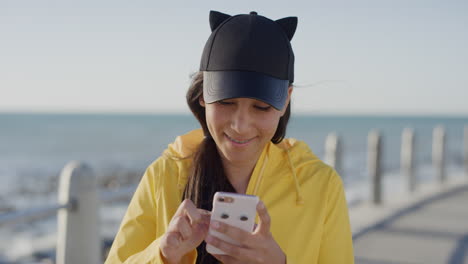 portrait-of-mixed-race-teenage-girl-texting-browsing-using-smartphone-social-media-app-happy-mobile-communication-on-seaside-beach