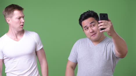 two young multi-ethnic handsome men together against green background