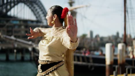 indian woman dancing classical dance in front of harbour bridge in sydney, australia - slow motion