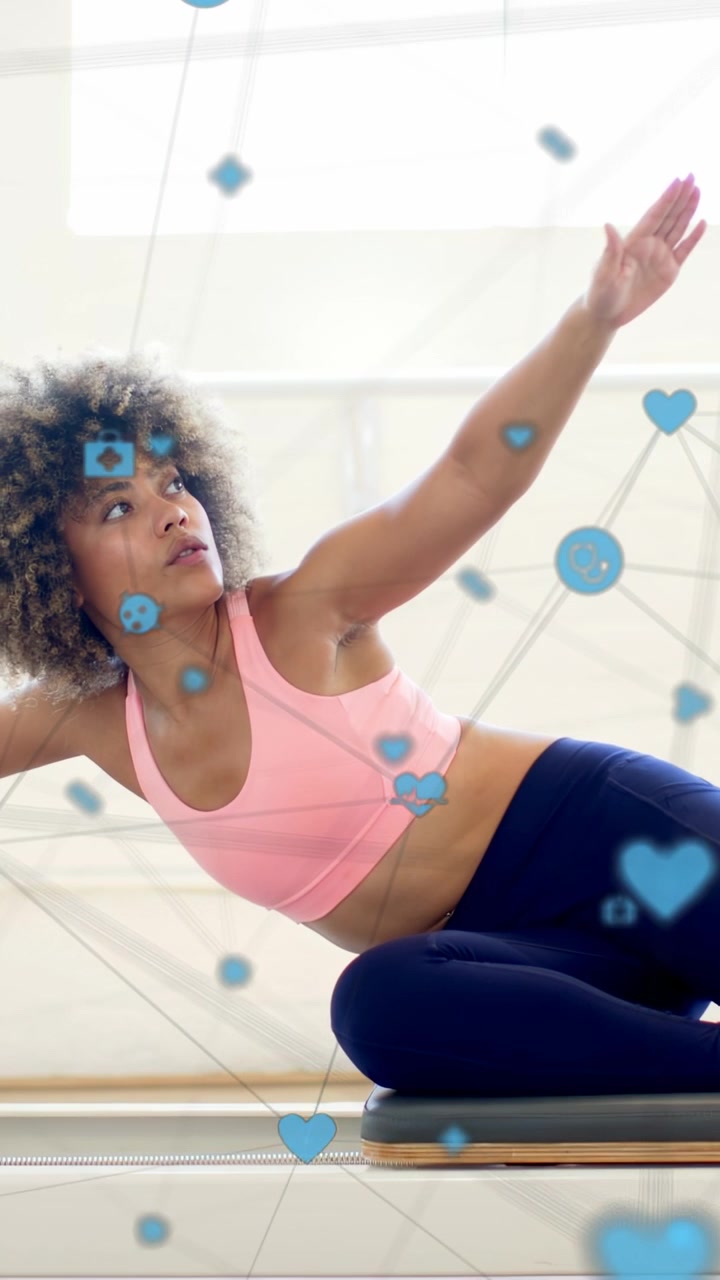 Vertical video: On cue woman doing seated reach and rotation for spine flex, blue icons drifting