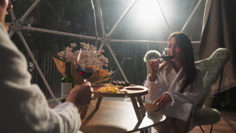 couple enjoying wine and snacks in a transparent igloo