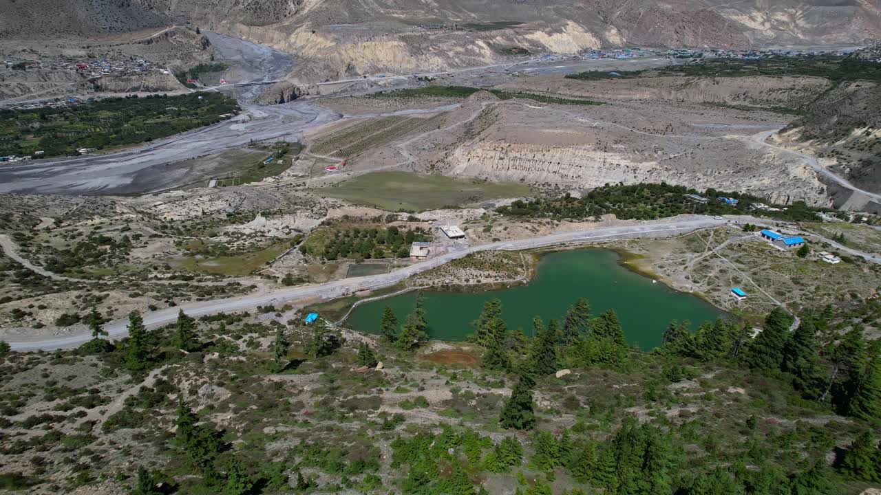 volando desde encima de la montaña revelando el pequeño lago dhumba alimentado por el hielo del monte nilgiri en el distrito de mustang de nepal - paralaje aéreo