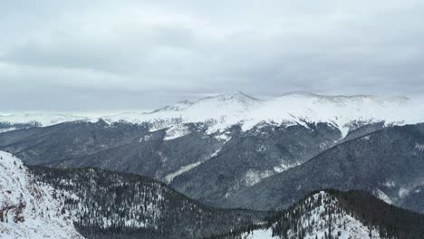 clouded sky over snowcapped hills with dense woods in winter park of colorado