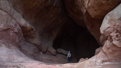 young woman walking from cave in sandstone rock, slow motion