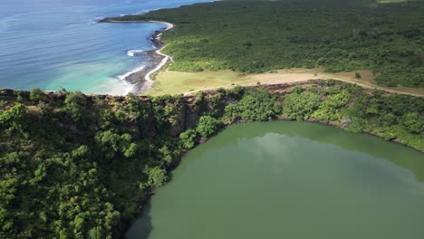drone footage of coastal crater lake with cliffs and ocean in the background