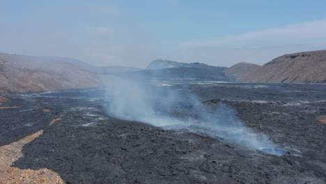 Amazing-aerial-view-of-Fagradalsfjall-volcanic-landscape,-drone-flying-backwards-through-smoky-lava-fumes,-Iceland,-day